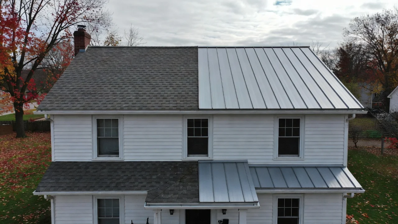 A split-view photo of a Michigan house showing one half with asphalt shingles and the other with a standing-seam metal